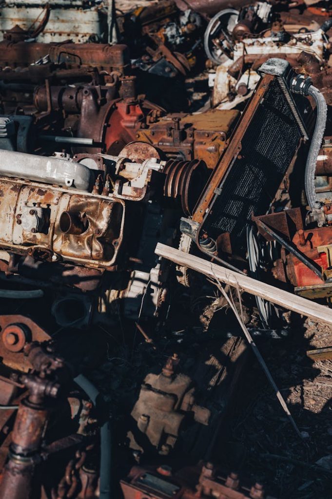 Close-up view of a heap of rusty, vintage auto parts in a junkyard, creating an industrial feel.